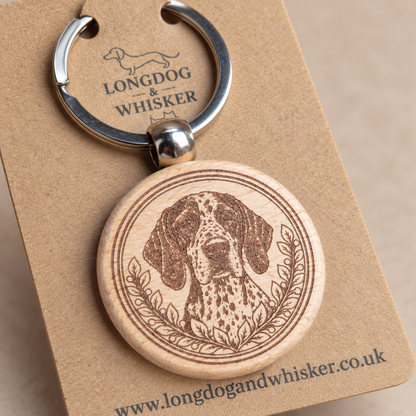 Close-up of the spotted English Pointer portrait, leafy border and rounded wooden keyring edge