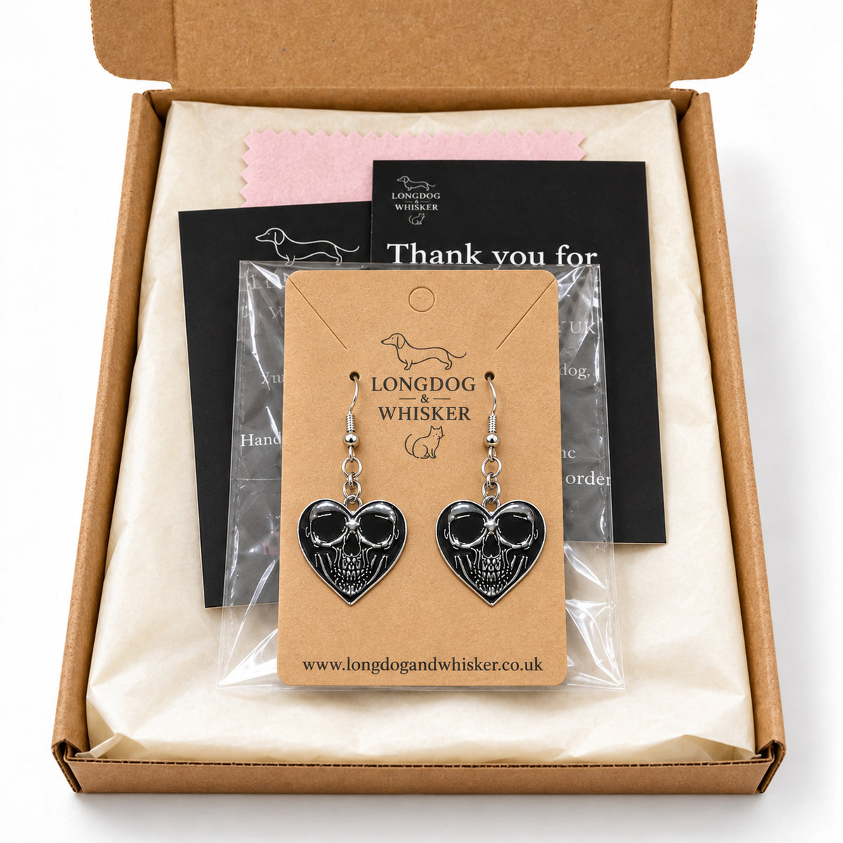 Front-facing skull heart drop earrings in Longdog & Whisker postal packaging