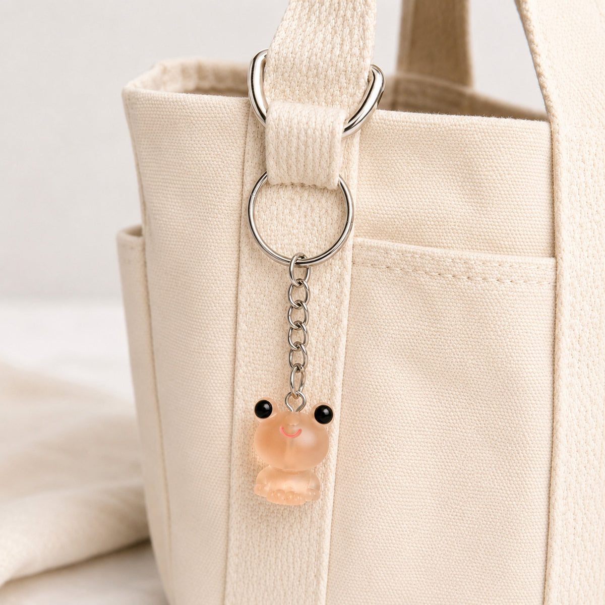 Frosted Frog in Apricot Keyring & Bag Charm attached to a cream canvas bag
