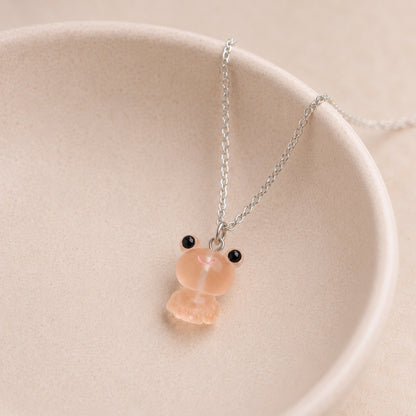 Frosted Frog in Apricot Necklace displayed on a ceramic bowl