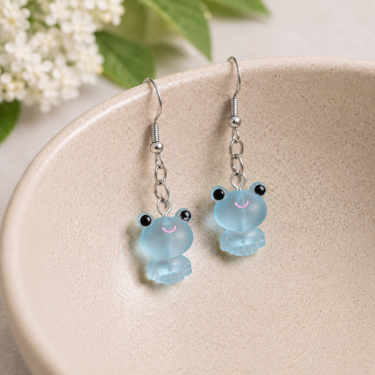 Frosted Frog in Aqua Earrings hooked over a ceramic bowl