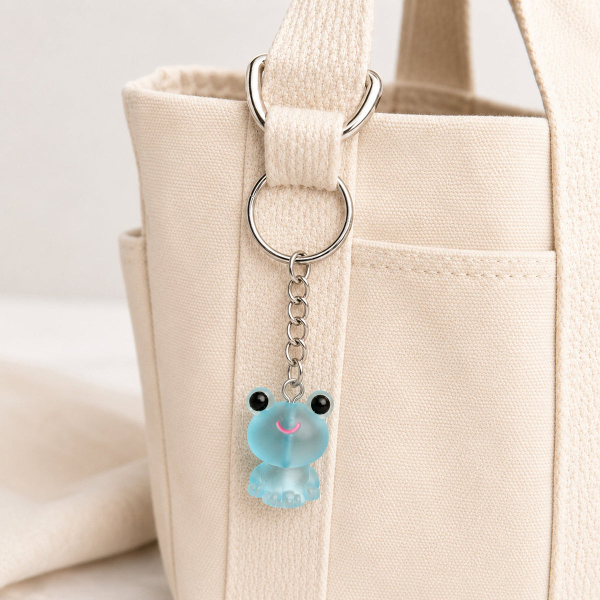 Frosted Frog in Aqua Keyring & Bag Charm attached to a cream canvas bag