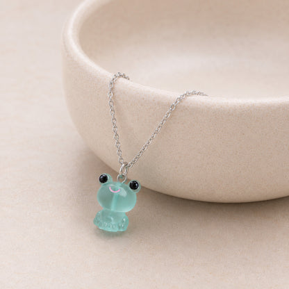 Frosted Frog in Aqua Necklace displayed on a ceramic bowl