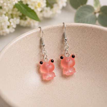 Frosted Frog in Coral Earrings hooked over a ceramic bowl