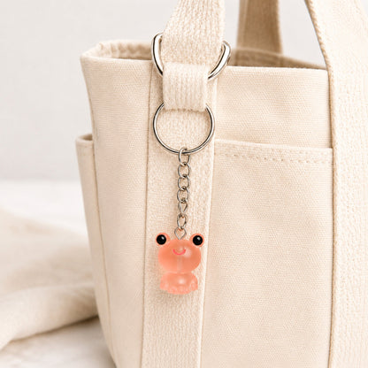 Frosted Frog in Coral Keyring & Bag Charm attached to a cream canvas bag