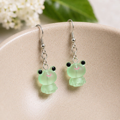 Frosted Frog in Green Earrings hooked over a ceramic bowl