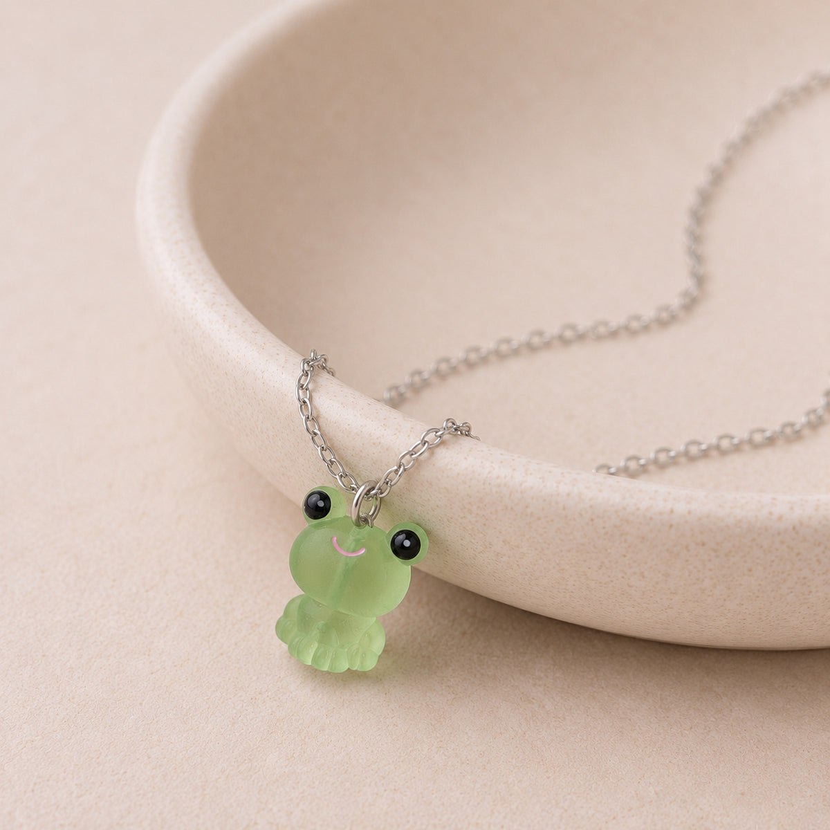 Frosted Frog in Green Necklace displayed on a ceramic bowl
