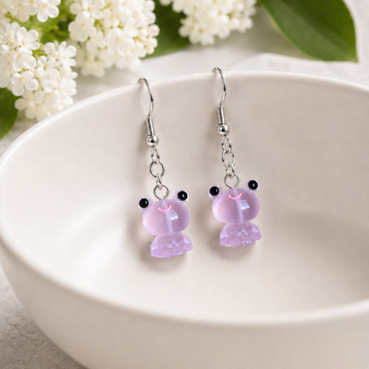 Frosted Frog in Lilac Earrings displayed on a ceramic bowl