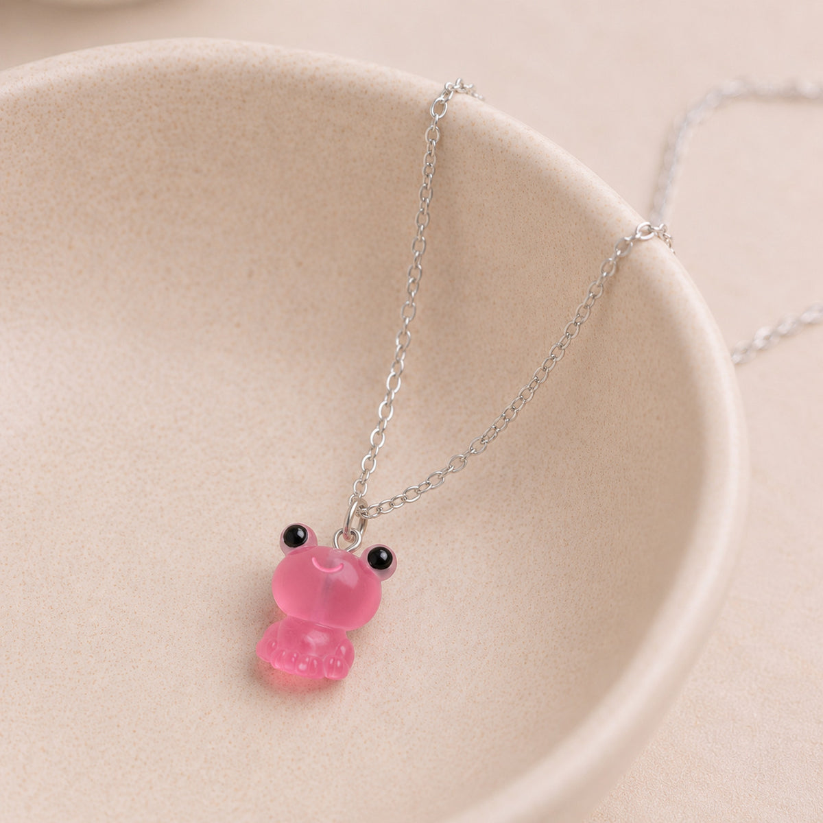 Frosted Frog in Pink Necklace displayed on a ceramic bowl