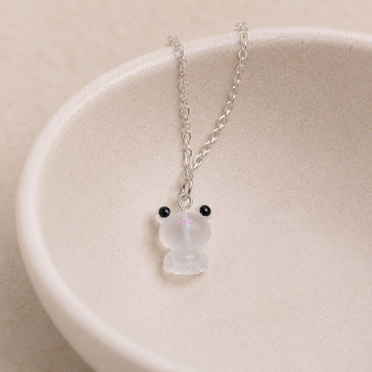 Frosted Frog in White Necklace displayed on a ceramic bowl