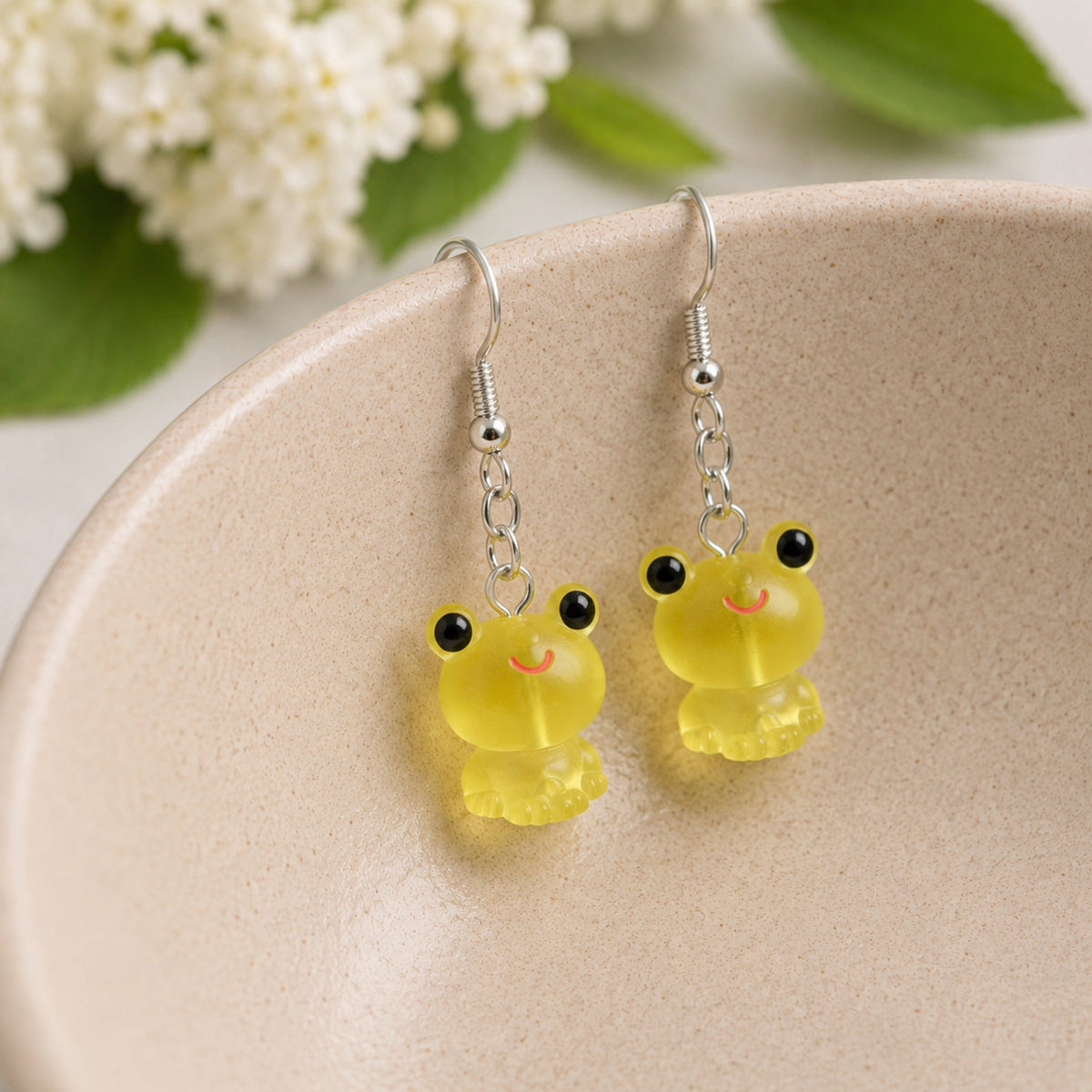 Frosted Frog in Yellow Earrings hooked over a ceramic bowl