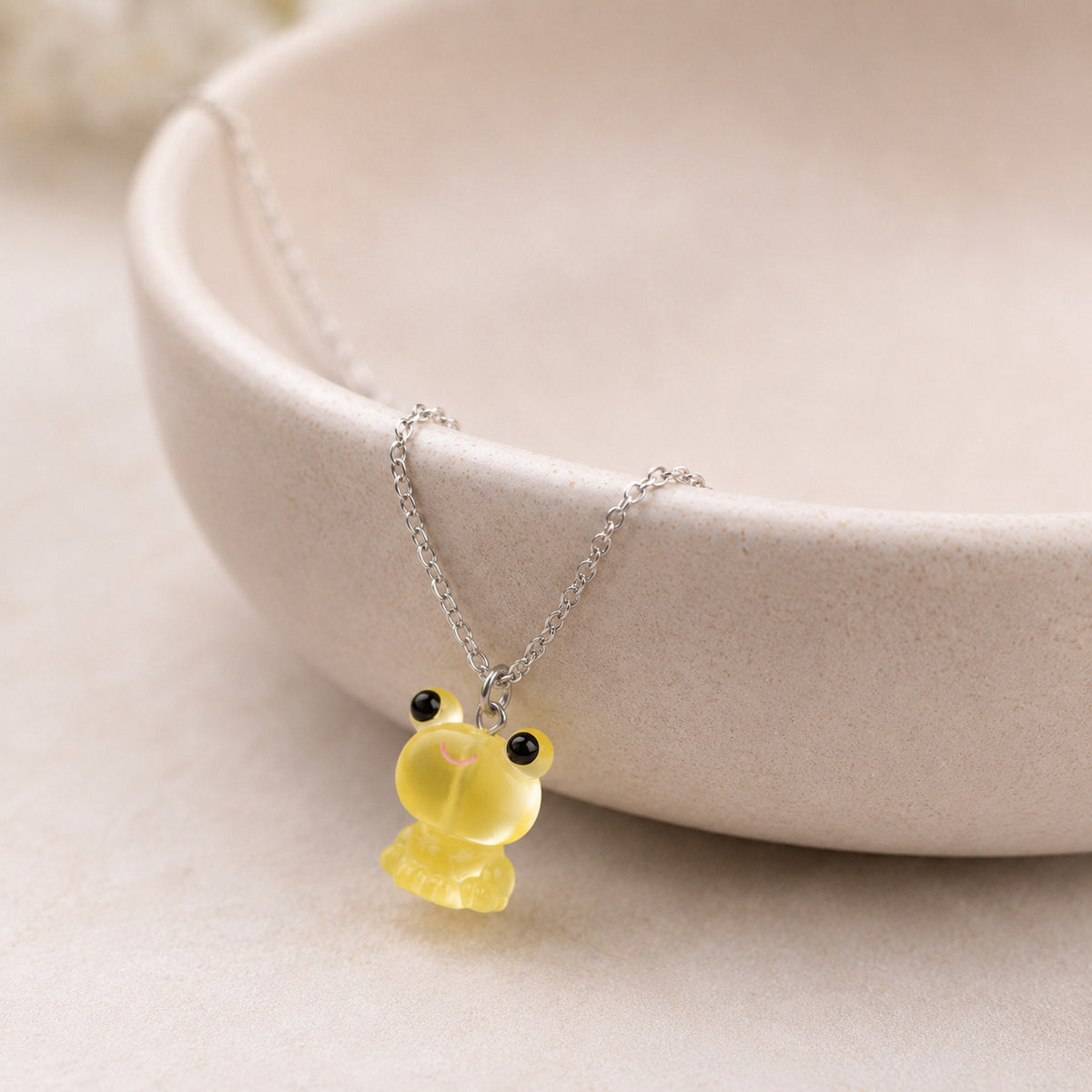 Frosted Frog in Yellow Necklace displayed on a ceramic bowl