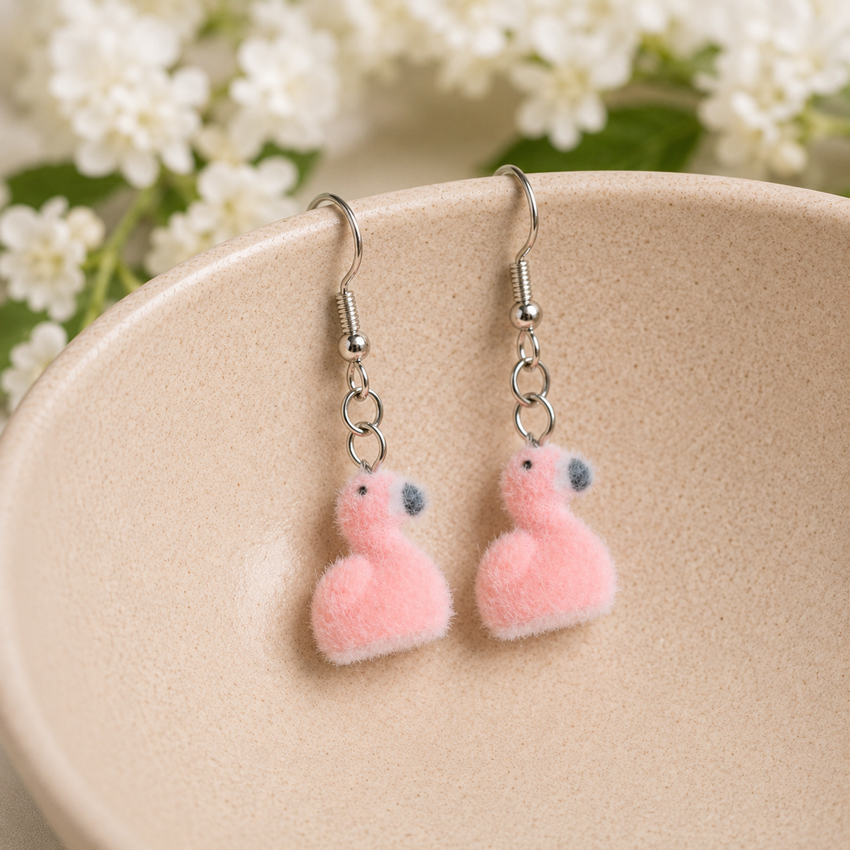Fuzzy Flamingo Earrings hanging over a ceramic bowl