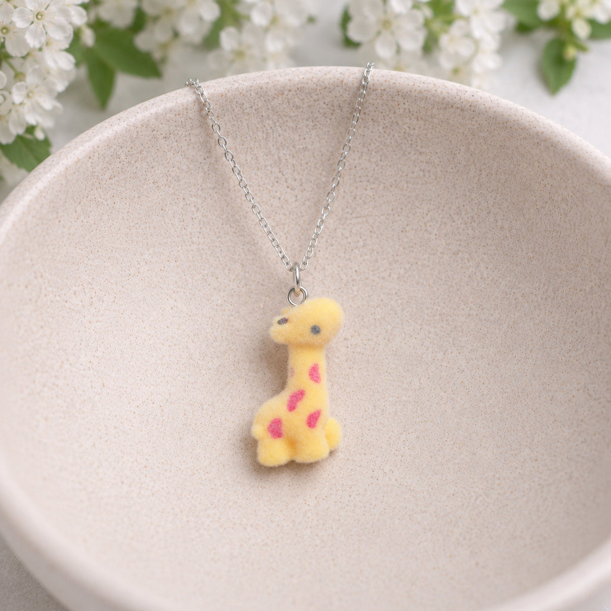 Fuzzy Giraffe Necklace displayed in a ceramic bowl