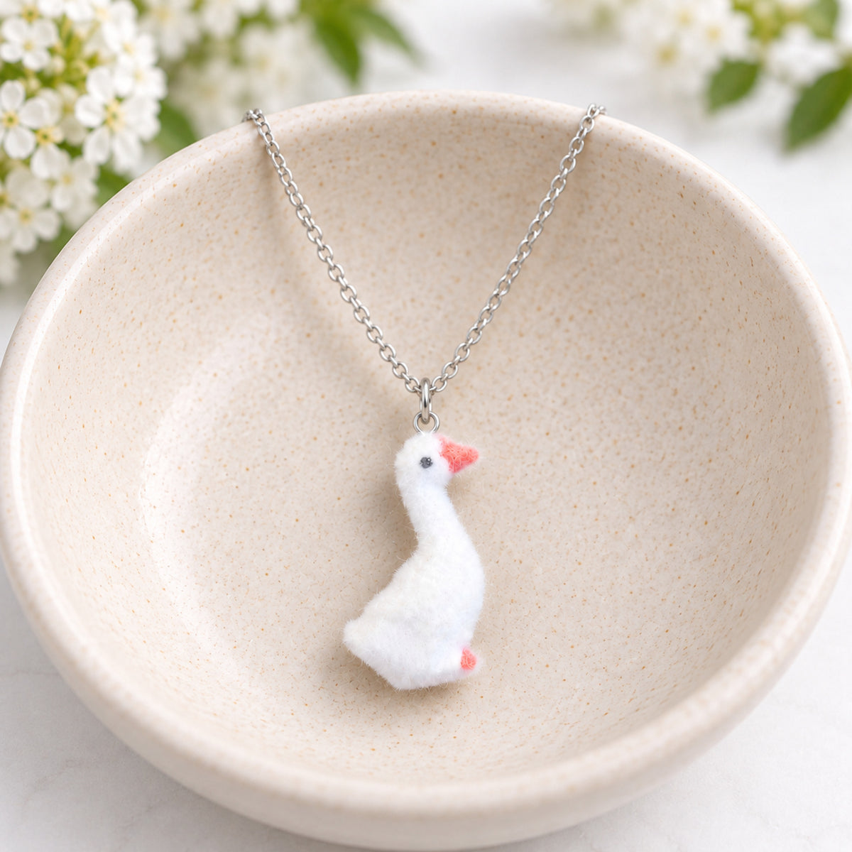 Fuzzy Goose Necklace hanging over a ceramic bowl