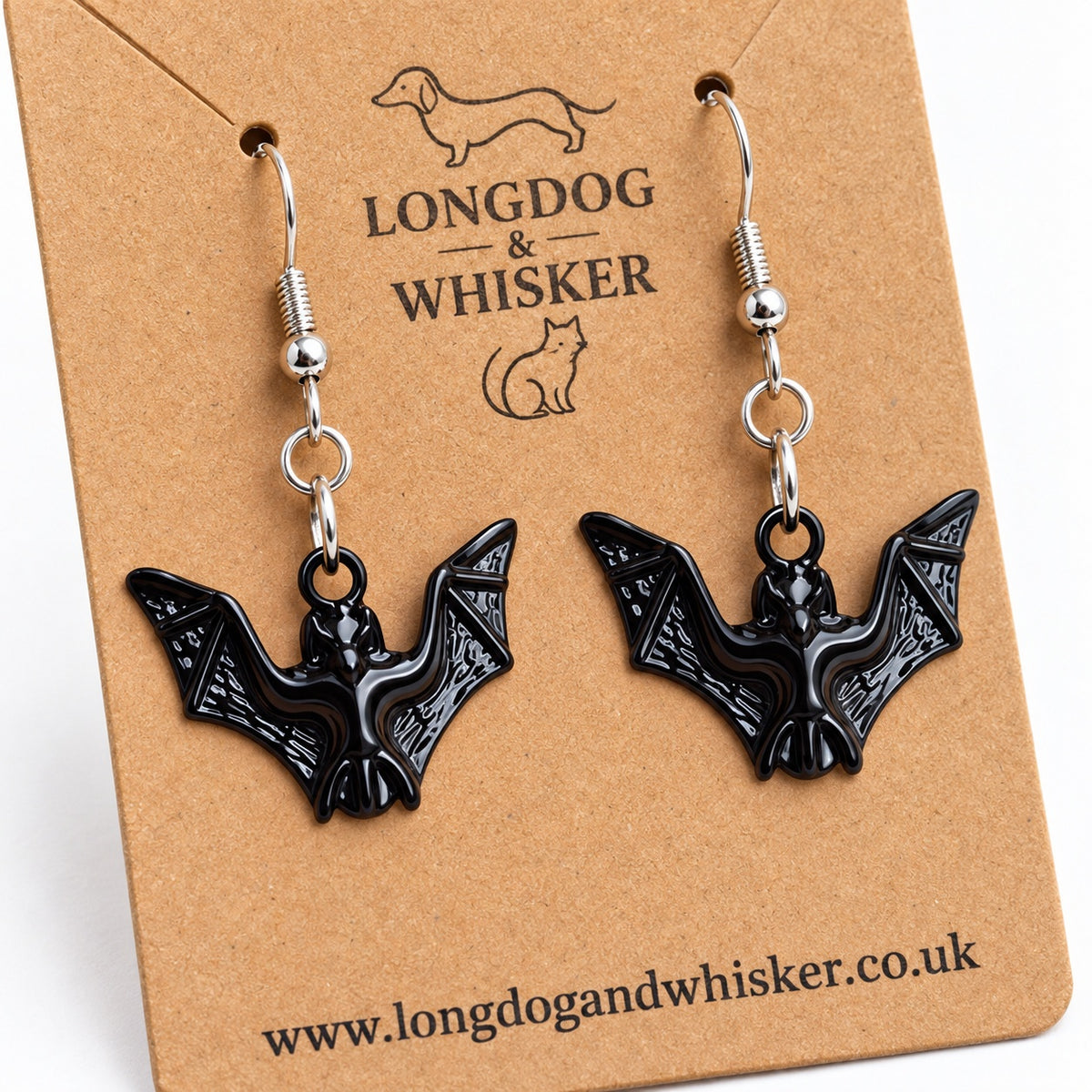 Close-up of glossy black bat earrings showing textured wings and silver-tone hooks