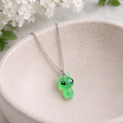Little Green Alien Necklace hanging over a ceramic bowl