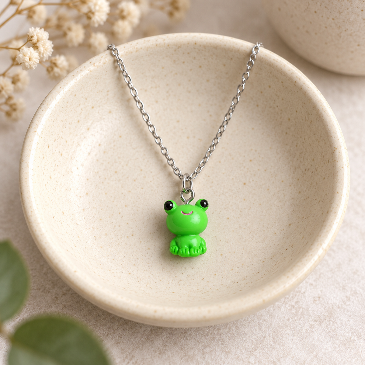 Green Frog Necklace Silver Chain displayed on a ceramic bowl