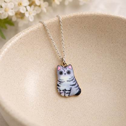 Grey tabby cat pendant necklace resting in a speckled ceramic bowl
