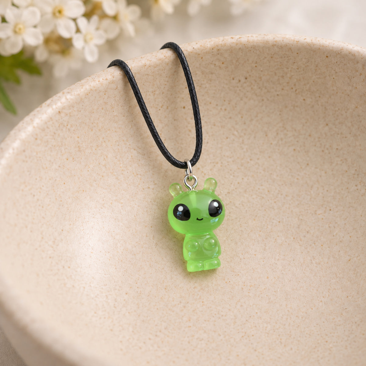 Little Green Alien Black Cord Necklace in a ceramic bowl lifestyle scene