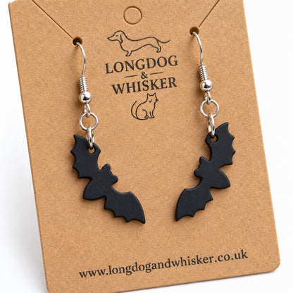 Close-up of matte black bat earrings showing scalloped wings and wingtip attachments
