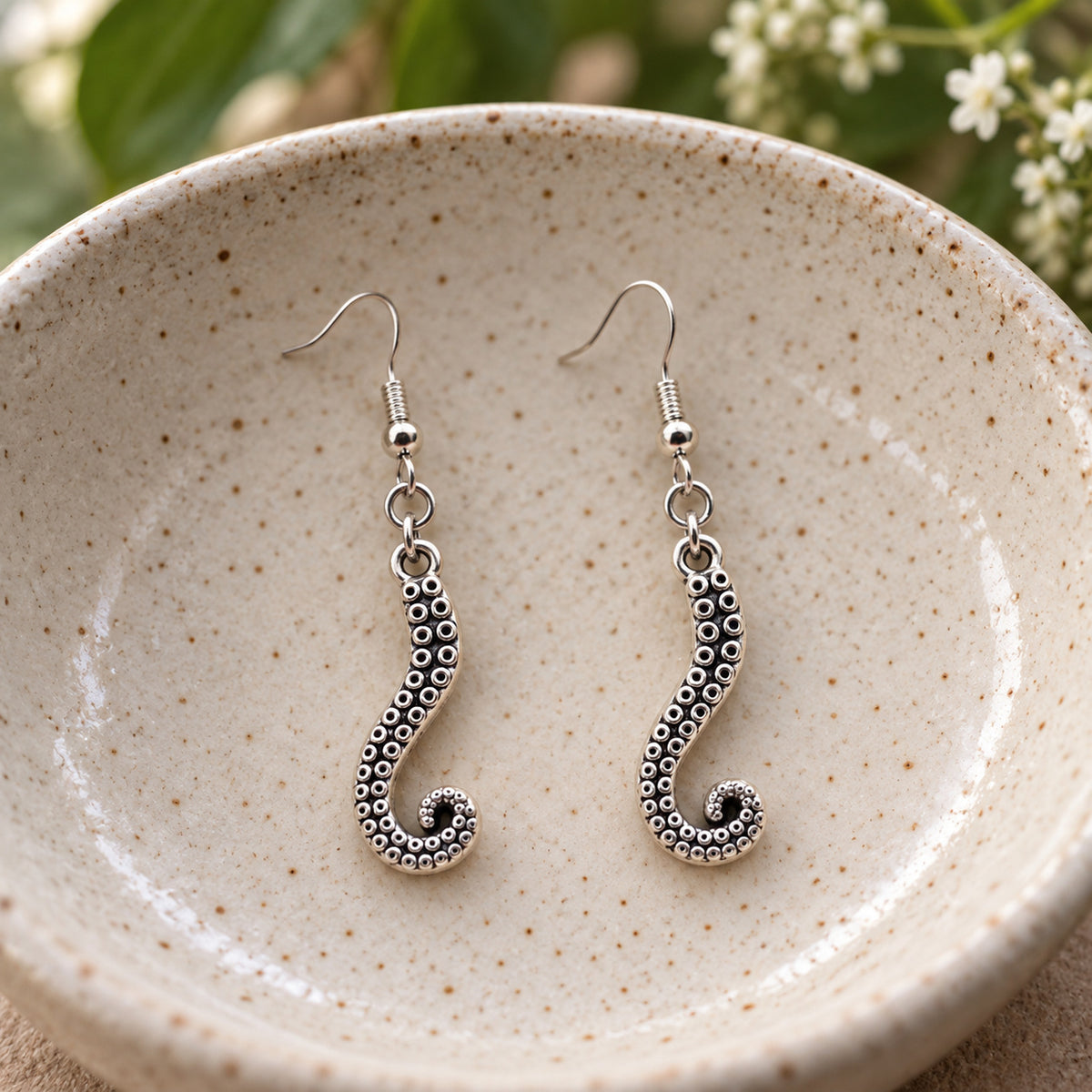 Octopus tentacle drop earrings in a speckled ceramic bowl