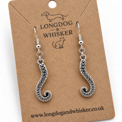 Close-up of silver-coloured octopus tentacle drop earrings on kraft card