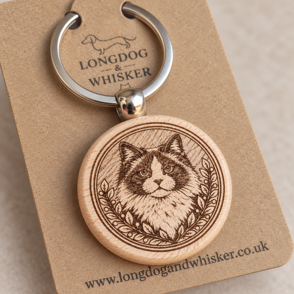 Close-up of Ragdoll portrait engraving, leafy frame and rounded wooden keyring edge