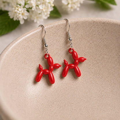 Red Balloon Dog Earrings hanging from a ceramic bowl