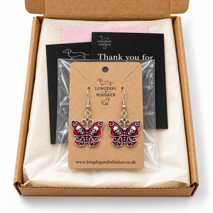Red skull butterfly earrings on their kraft card in Longdog & Whisker gift packaging