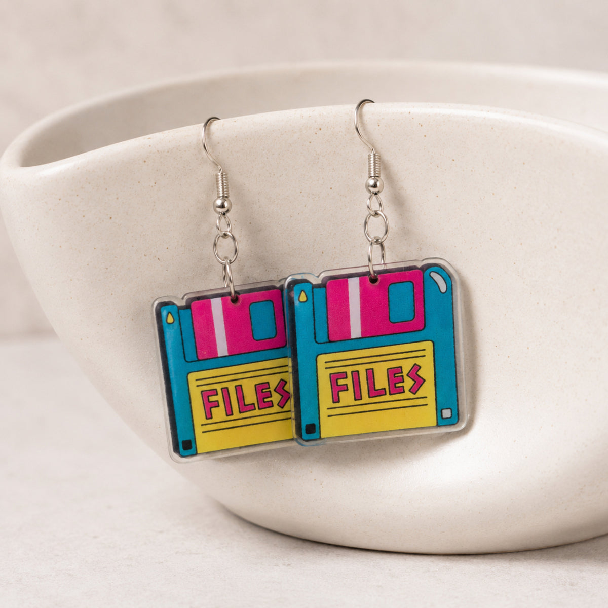 Retro Floppy Disk Earrings hanging from a ceramic bowl