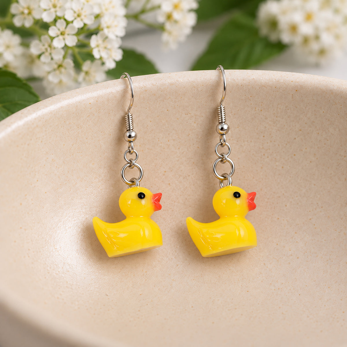 Yellow rubber duck earrings resting in a speckled ceramic bowl