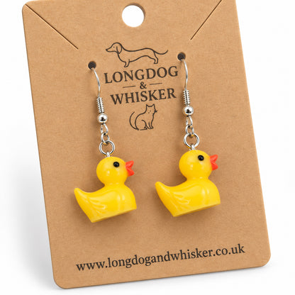 Close-up of rubber duck earrings showing glossy charms and silver hooks