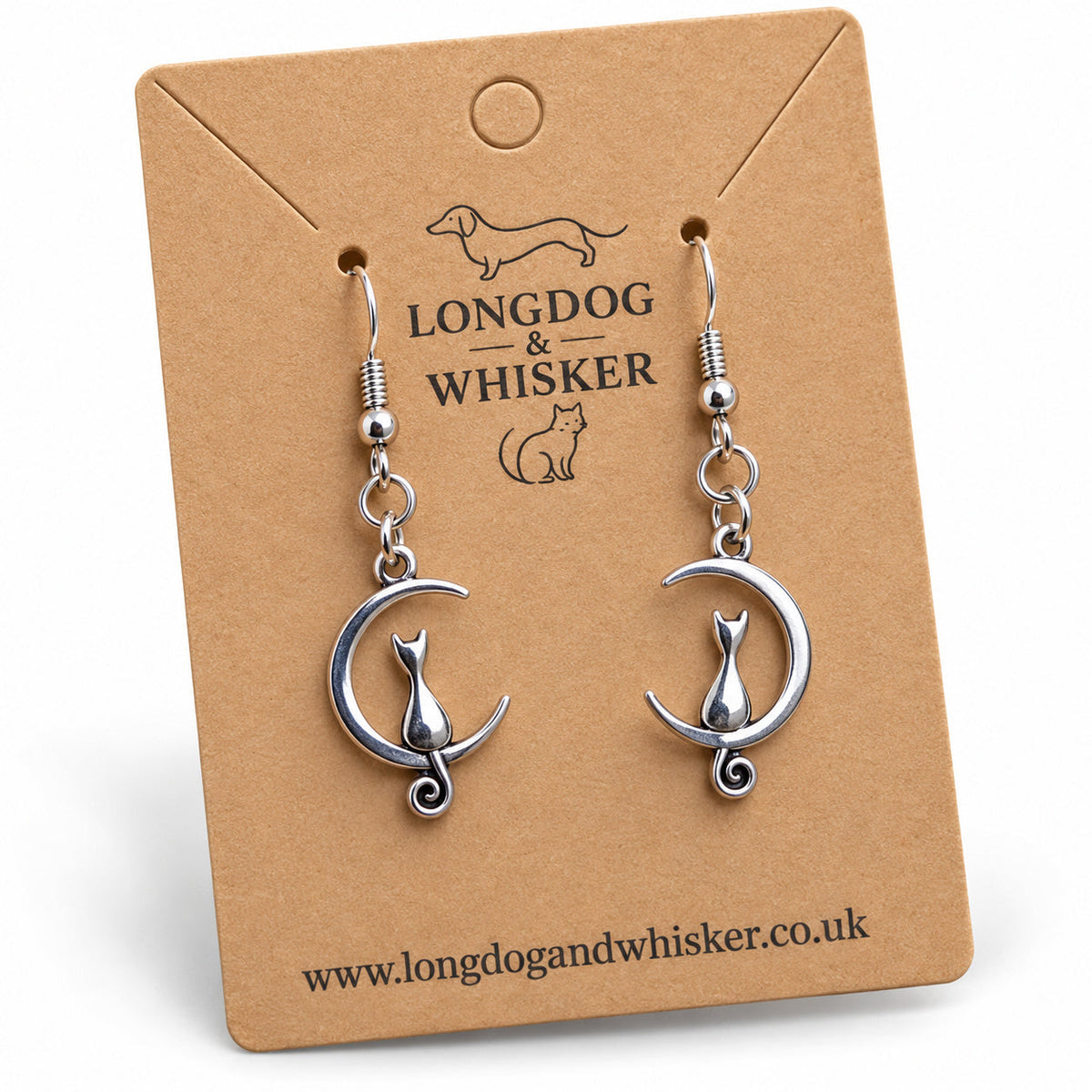 Close-up of silver cat and crescent moon earrings with curled tails and fishhook fittings.