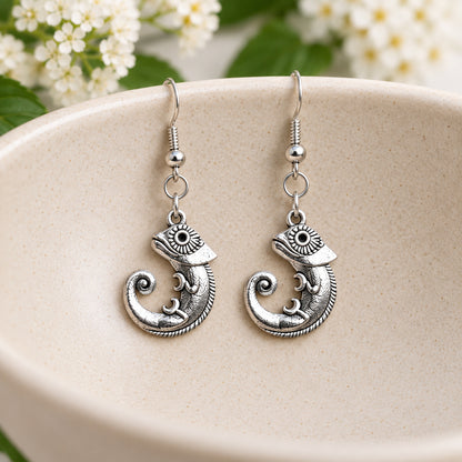 Silver-tone chameleon earrings hanging in a speckled ceramic bowl