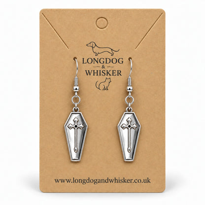 Silver coffin cross drop earrings on a Longdog & Whisker kraft card.