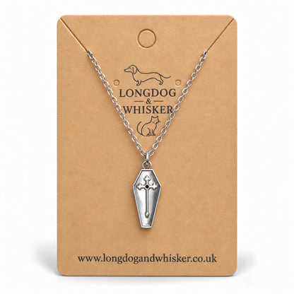 Silver coffin cross necklace on a Longdog & Whisker kraft card.