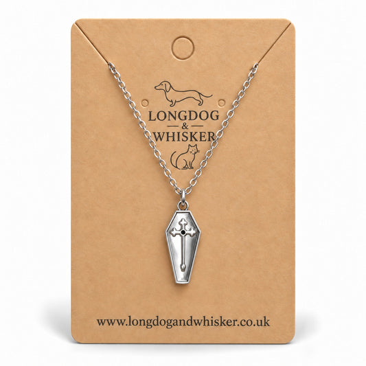 Silver coffin cross necklace on a Longdog & Whisker kraft card.