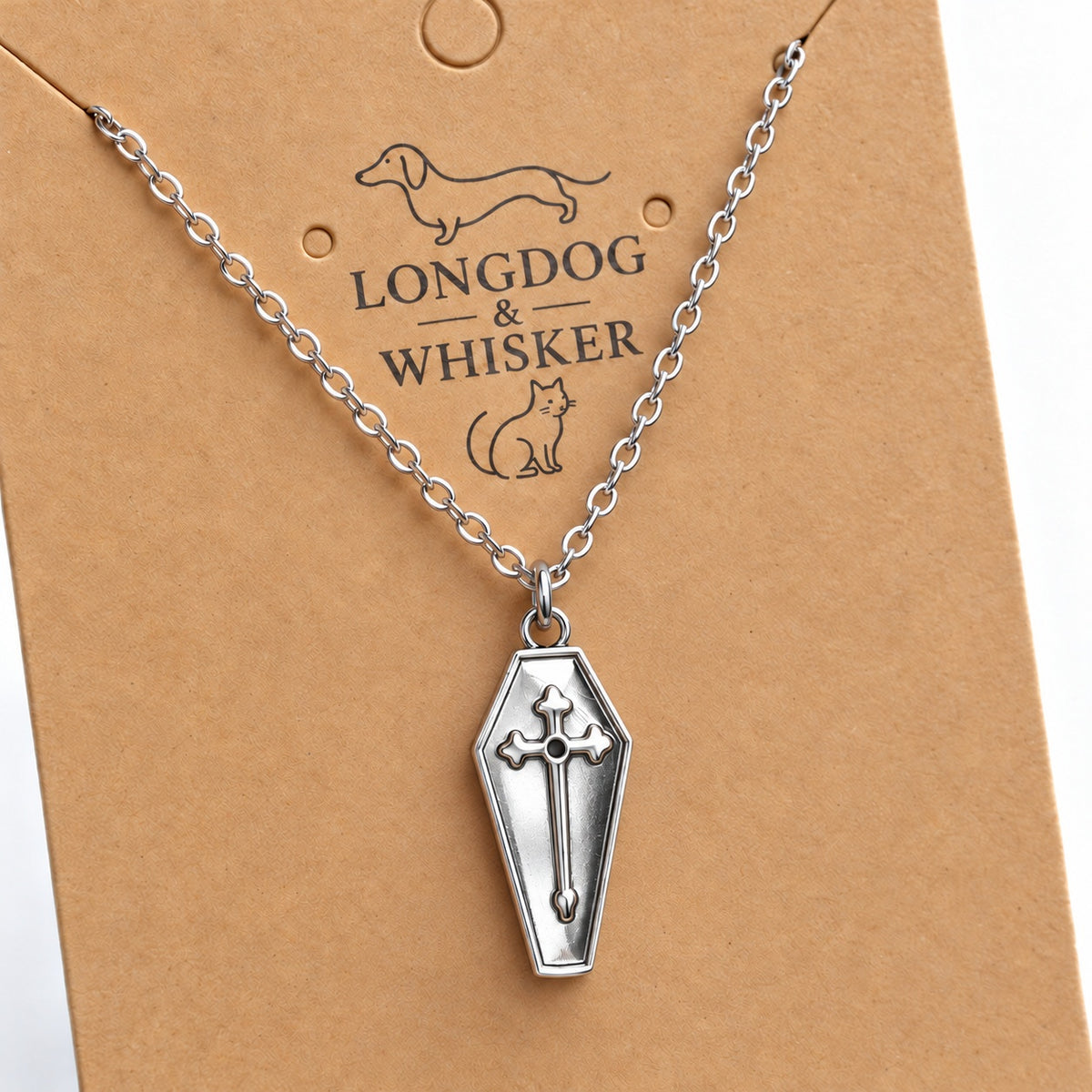 Close-up of the silver-tone coffin pendant with raised cross and silver chain.