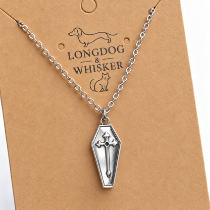 Close-up of the silver-tone coffin pendant with raised cross and silver chain.