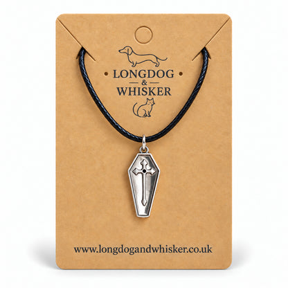 Silver coffin cross necklace on black cord displayed on a Longdog & Whisker kraft card.