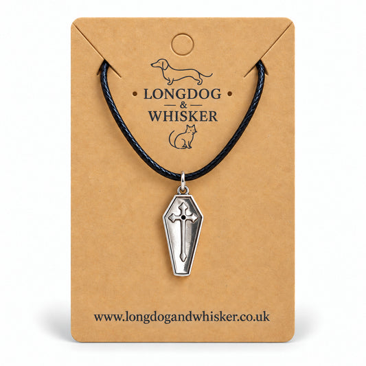 Silver coffin cross necklace on black cord displayed on a Longdog & Whisker kraft card.