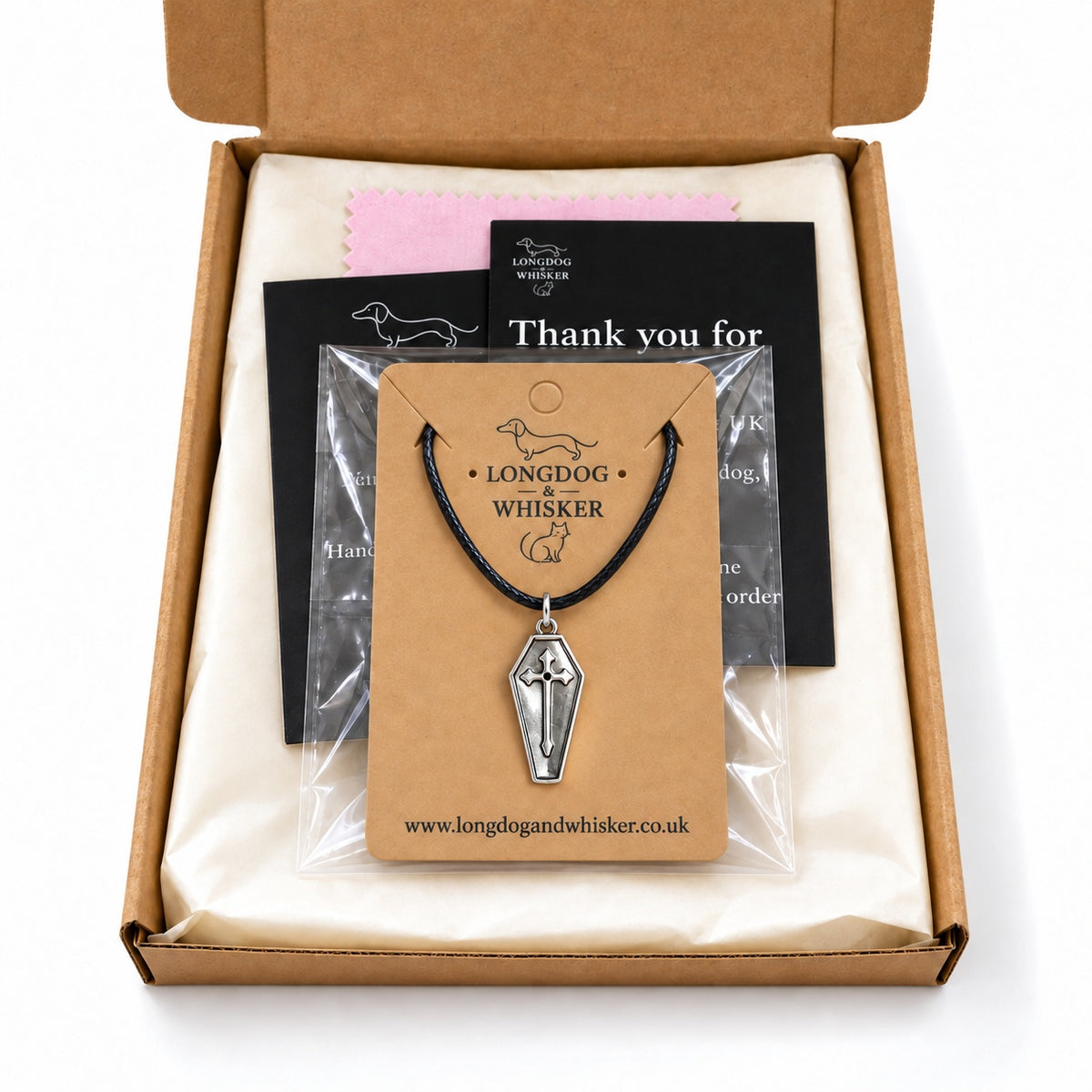 Silver coffin cross necklace on black cord in Longdog & Whisker postal packaging.