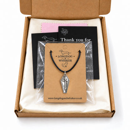 Silver coffin cross necklace on black cord in Longdog & Whisker postal packaging.