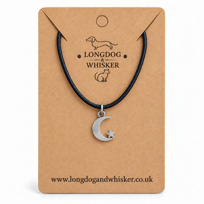Silver crescent moon and star necklace on black cord on its kraft product card