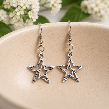 Silver double star earrings resting in a speckled ceramic bowl.