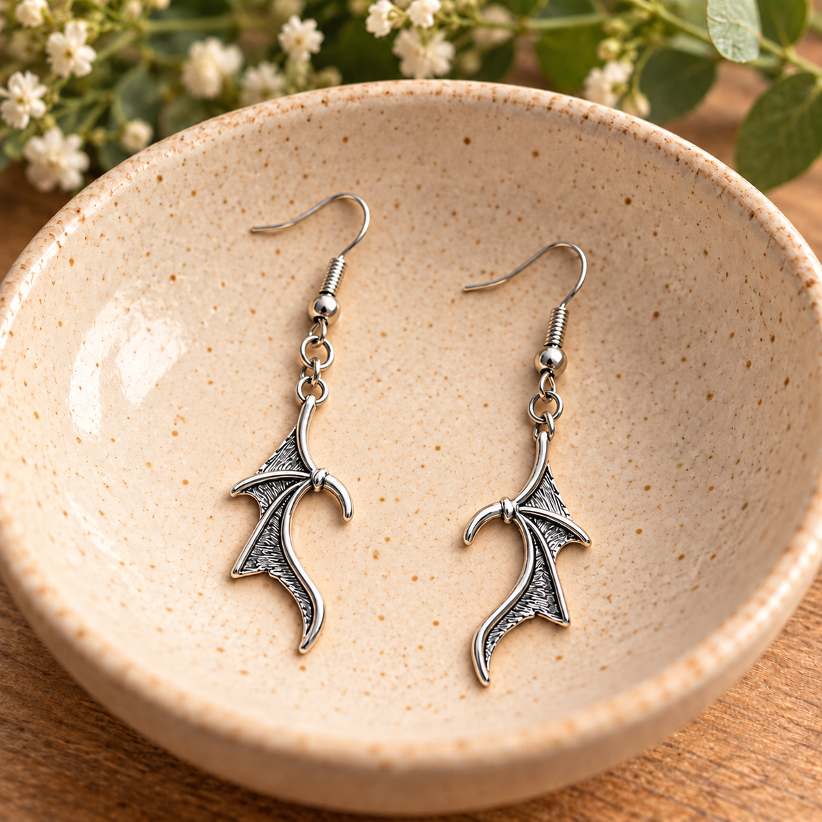 Silver Dragon Wing Drop Earrings in a speckled ceramic bowl