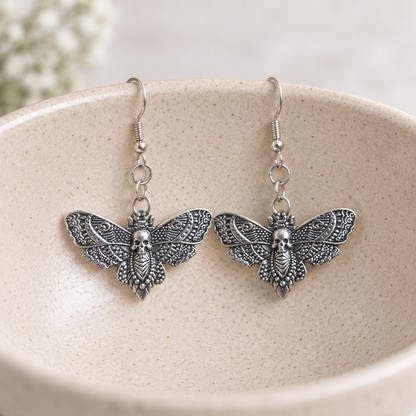 Silver Skull Moth Earrings styled on a ceramic bowl