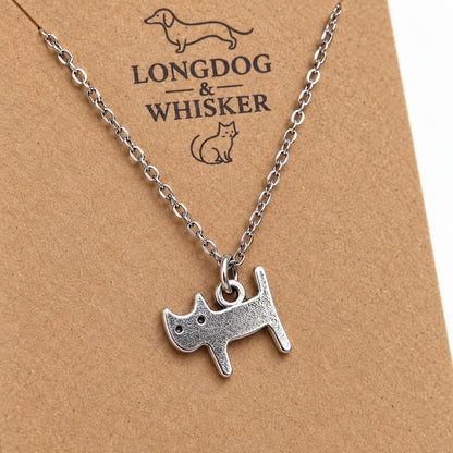 Close-up of the silver cat charm with two tiny eyes, pointed ears and an upright tail