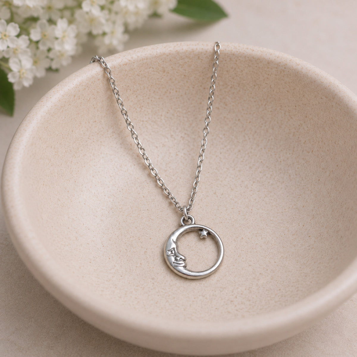 Silver moon and star necklace in bowl lifestyle photo